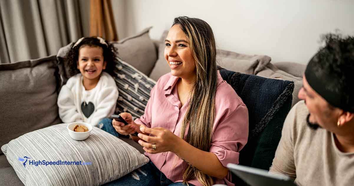 Family sitting together on the couch using a remote for streaming