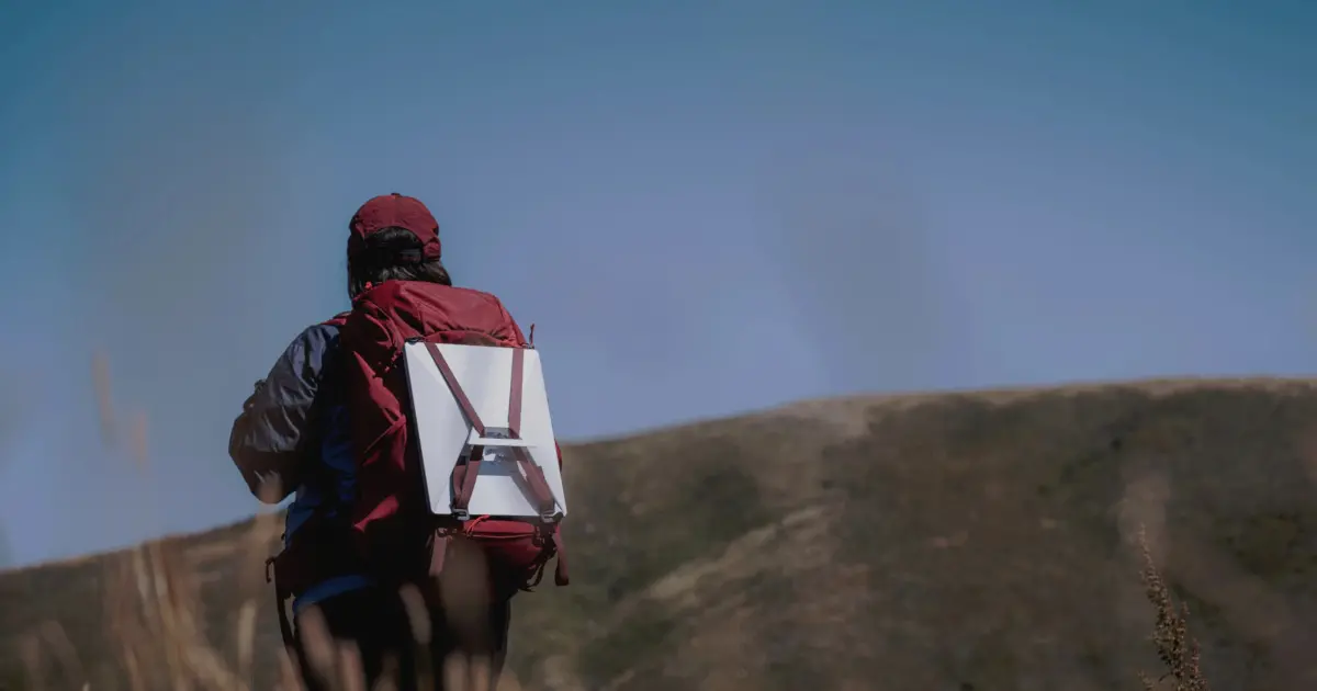 Man carries Starlink Mini dish in backpack